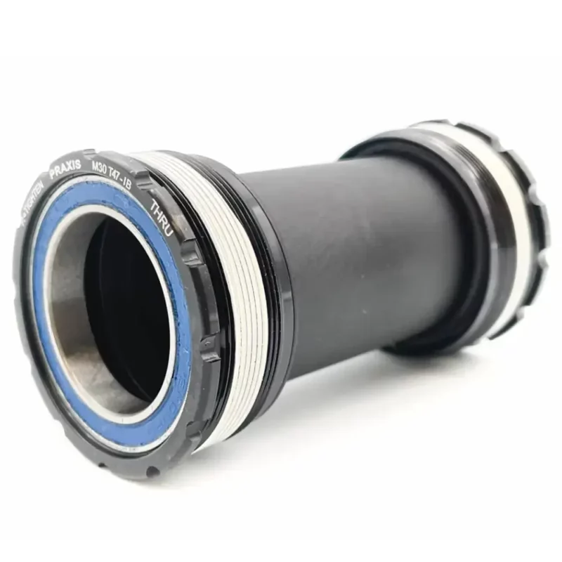 A black Praxis M30 Thru T47 Inboard Bottom Bracket with blue seals.