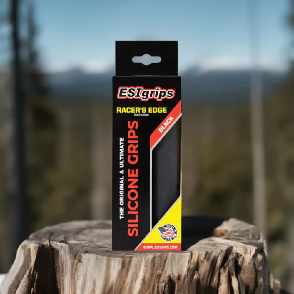 A set of black ESI Racer’s Edge Grips in retail packaging on a tree stump.