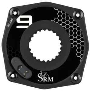 Image of a black SRM power meter with a circular shape and a central hole. It features a hexagonal pattern on the right side and the number "9" in white on the left. The SRM logo is at the bottom center. Four bolts are at the corners.