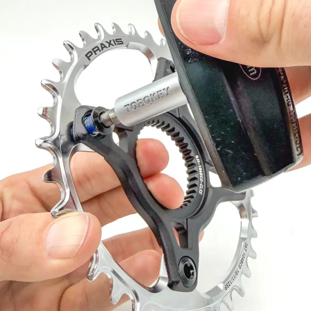 A Praxis Works E-Bike MTN 1x 104 BCD Chainring with Silver PVD coating being installed on black a e-MTB spider