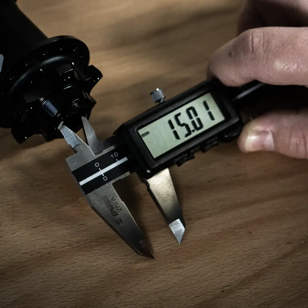 A black and silver Unior Digital Vernier Caliper being used to measure the inner diameter of a hub