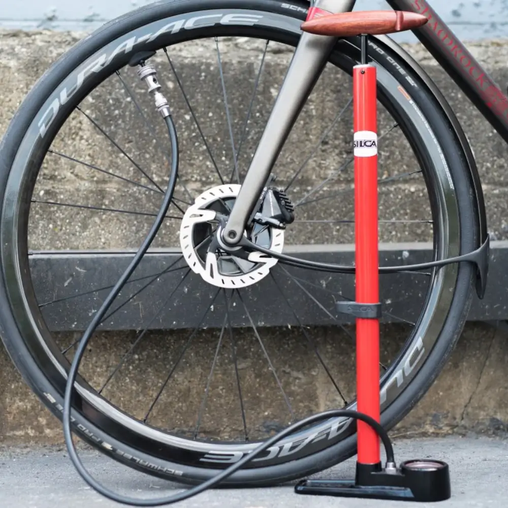 A red Silca Pista Floor Pump being used to pump a tire